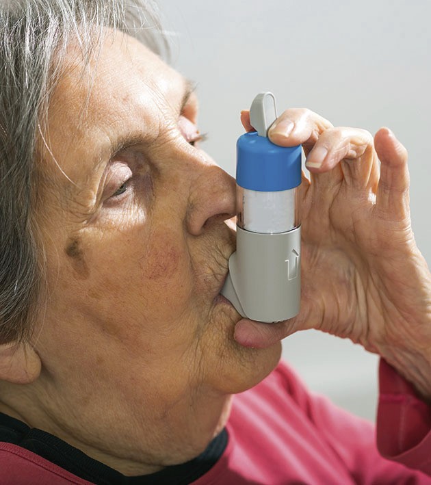 Ältere Patientin, die mit einem Dosieraerosol inhaliert